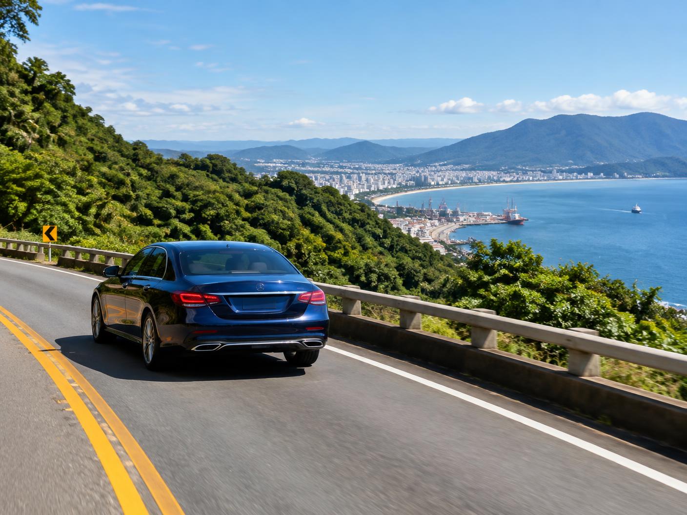 Carro particular em estrada costeira com vista para Santos, o porto e a Serra do Mar